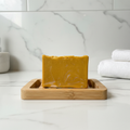 Sweet Banana Cream soap on a bamboo dish with white marble countertop and soft bathroom lighting