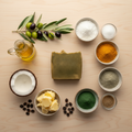 BY RICEL Terra Bar artisan soap bar surrounded by its key ingredients — olive oil, coconut, shea butter, castor oil, spirulina, turmeric, bentonite clay, goat milk powder, colloidal oatmeal, and sugar — on a warm wooden surface